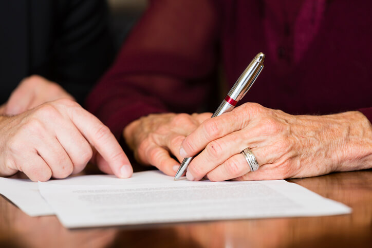Woman signing estate planning documents with attorney
